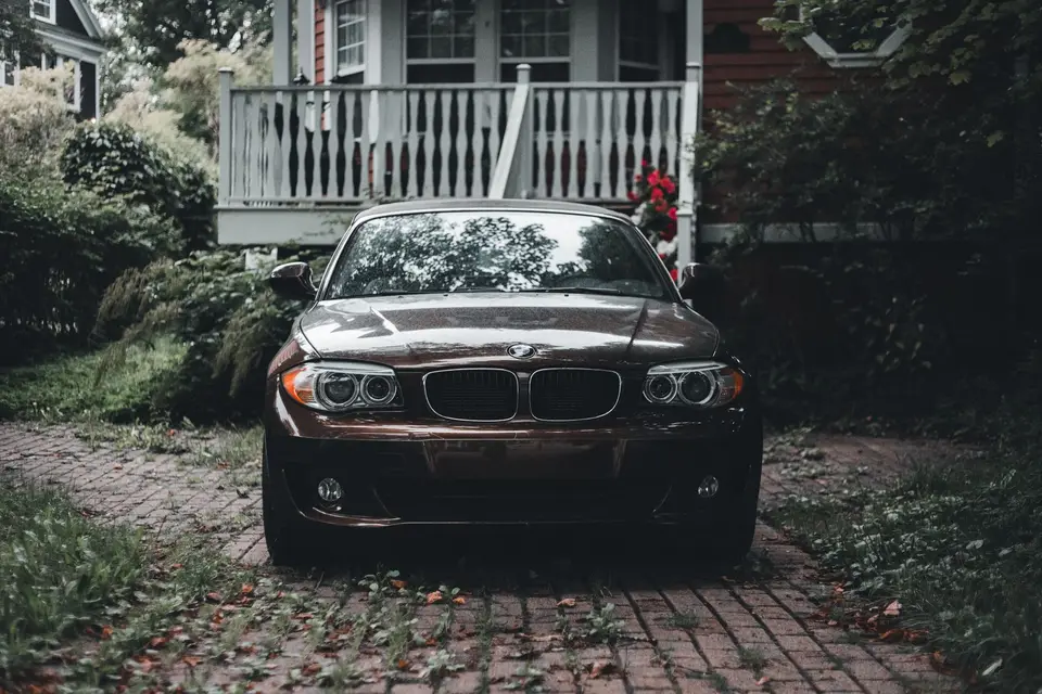 A car parked on a brick-paved path beside a wooden house