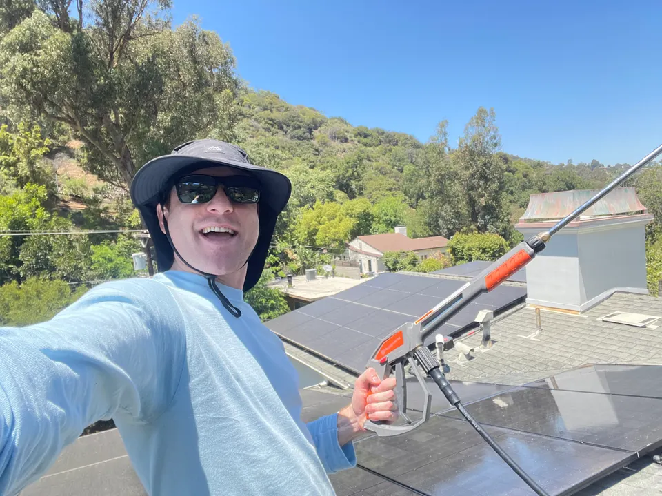 Logan in a bucket hat and sunglasses on a rooftop with solar panels in the LA hills