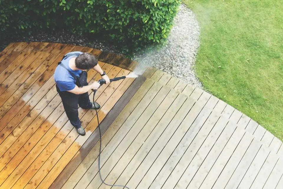 Overhead view of a technician washing a wood deck, clean boards emerging